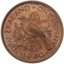 A proof penny featuring a tūī bird perched atop the branch of a kōwhai tree, surrounded by flowers and leaves, and encircled by the text "NEW ZEALAND - ONE PENNY - 1940"