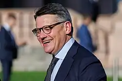 Portrait of a middle-aged white man wearing a dark suit and glasses