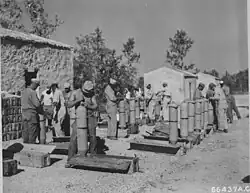 A black and white photograph of multiple men unpacking and loading cylindrical bombs