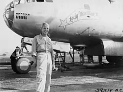 A black and white photograph of a uniformed military pilot standing in front of an aircraft