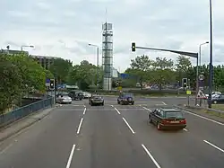 Four lanes of traffic approach a set of traffic lights.