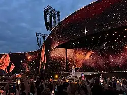 Adele sings into a microphone wearing a navy gown