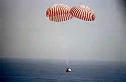 Spaceship descends over ocean with parachutes