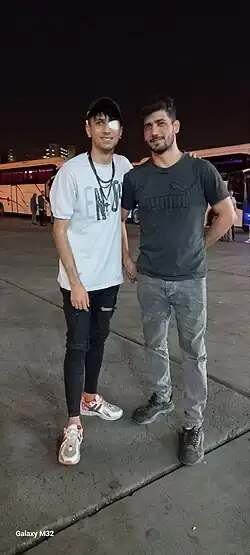 From left to right, Artin Ahmadi and Alvand Alvandiani standing side by side at a bus port.