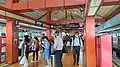 A photograph of Choa Chu Kang station's LRT platform. It consists of read beams which support an inverted 'V' shaped roof. The platform is crowded