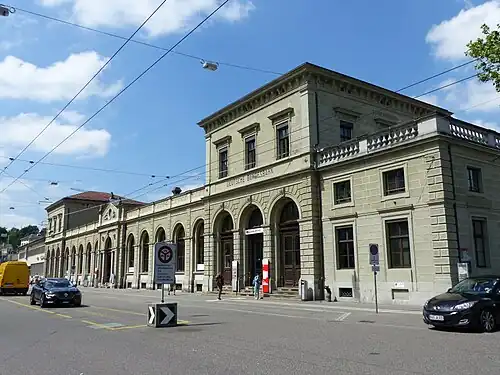 Wide two-story stone building with two three-story towers
