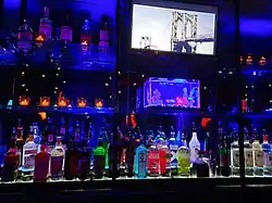 Bar outfitted with bottles of alcohol and a small aquarium under neon lights