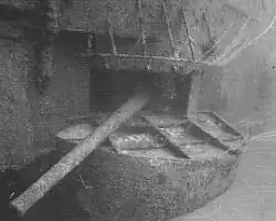 Underwater photograph of a gun protruding from an opening in the side of a sunken ship.