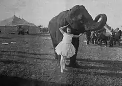 Black and white film still showing a woman next to a circus elephant