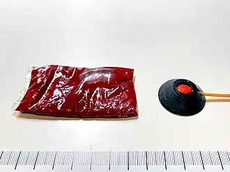 A 15&nbsp;g packet of fake blood next to a 0.5 grain squib with a solid polycarbonate shield.