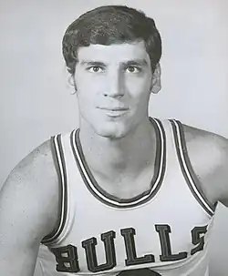 A black-and-white photo of a white man wearing a white uniform that says "Bulls" on it.