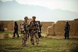 British soldiers wearing desert combat dress including body armour covers and bush hats.
