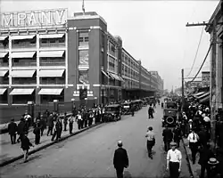 Masses of men throng the streets outside a building.