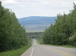 Chena Hot Springs Road at mile 14 (km 22), looking westbound and downhill with the Little Chena River valley at the bottom.