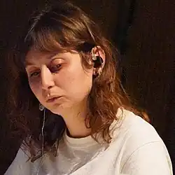 Portrait photo of a young brunette woman in a white shirt looking downwards