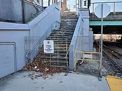 A fenced-off set of concrete stairs next to a railway line