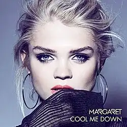 Margaret posing in front of a grey backdrop while biting in a black material.