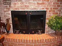 Custom-fitted fireplace insert with large glass doors, and a large heat exchanger for efficiency