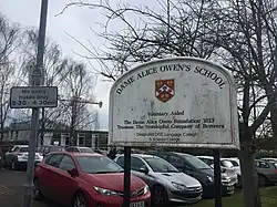 A sign at the front of the school which includes the text "Designated DfEE Language College & Science College"