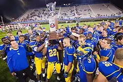 Football players in blue and yellow hold up a trophy