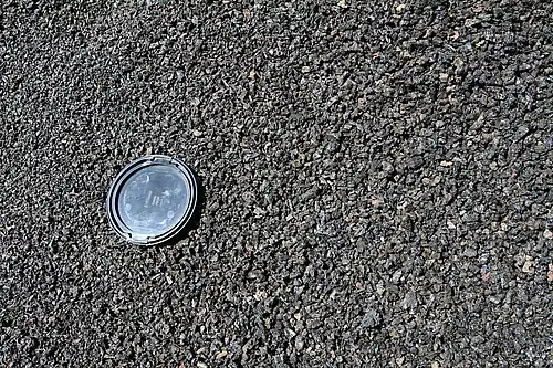 Cinders of the cone of Caldera de los Cuervos on Lanzarote, with camera lens cap (77&nbsp;mm (3&nbsp;in) across) for scale