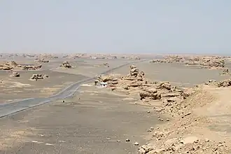 Yardang rock formations in a desert, a road crossing the area