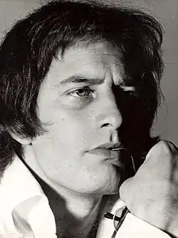 Black and white close up of a clean shaven man with long hair wearing a white shirt