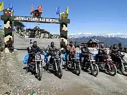 Six motorcyclists at a war memorial in the mountains