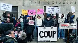 Protest at the Department of Treasury; in the center, two women can be seen holding signs with Musk's gesture, calling him a felon and a thief.