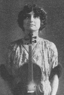 Estelle Gray Lhevinne holding a violin in front of her body