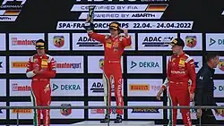 Antonelli lifting his trophy after winning at Spa-Francorchamps in the 2022 ADAC F4 Championship, between Rafael Câmara and Charlie Wurz