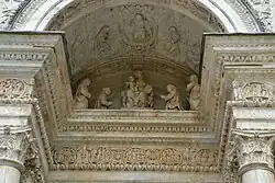 Relief under the portal arch portraying two couples of Carthusians paying homage to the Virgin and Child.