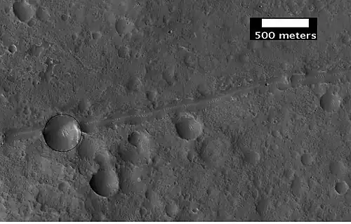 Close-up of a possible fault in Mare Acidalium, as seen by HiRISE under the HiWish program. A circle is drawn around crater to show that it may be off round because of movement of the fault. Many other faults are in the region.