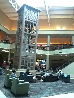 The interior of Genesee Valley Center, showing an open shopping mall concourse with several stores and an elevator