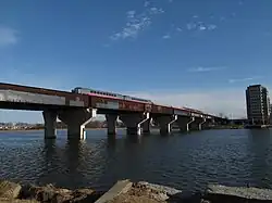 A passenger train crossing a high girder bridge over a river