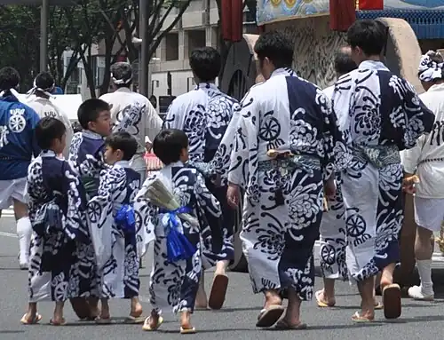 Adults and children in identical yukata at the Gion Matsuri. Children's yukata are the same size, but taken in with pleats as in the previous image.