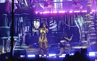 SZA performing in front of a backdrop bathed in purple and blue lighting
