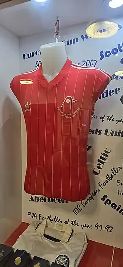a red football shirt showing the Aberdeen FC insignia and text showing it is from the European Cup Winners Cup final 1983
