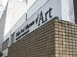 Close up of the museums name on the wall above square-shaped earth-tone bricks.