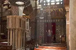 Ornate wooden pulpit with geometric patterns and decorative screen with religious iconography