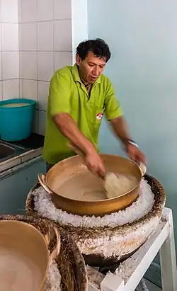 A man stirs helado de paila in a bronze basin over ice.