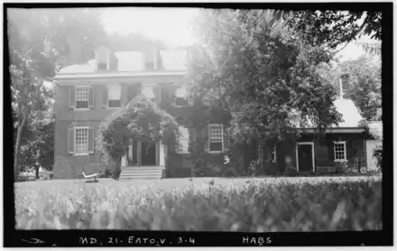 two and a half-story brick house with multiple chimneys and wing on the right