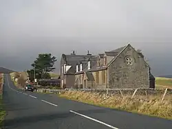 A short terrace of stone houses by a tarmacked road. The area is an upland setting.