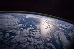 Image 20A view of Earth with different layers of its atmosphere visible: the troposphere with its clouds casting shadows, a band of stratospheric blue sky at the horizon, and a line of green airglow of the lower thermosphere around an altitude of 100&nbsp;km, at the edge of space (from Earth)