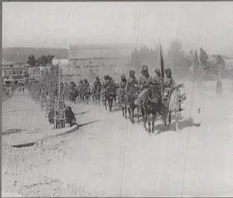 A photograph showing a regiment of Indian cavalry riding their horses in a column through Damascus