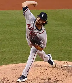 A man in a gray baseball jersey and navy blue cap