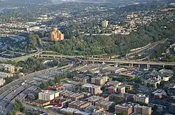 Aerial view of a freeway interchange with flying ramps situated over a dense urban neighborhood.