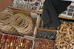 Open cardboard boxes seen from above. One holds two piles of crowns of thorns, another holds rosaries, another holds crucifixes, another holds magnets with Holy Land sites, another holds burnable sticks.
