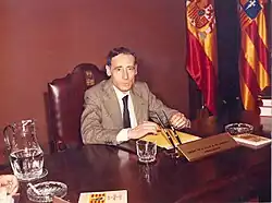 A man in a suit sitting at a desk.