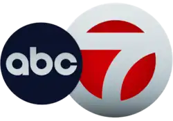 A white 7 in a white circle with red filled in. The ABC network logo, a black disk with lowercase letters a b c, overlaps it on the left side.